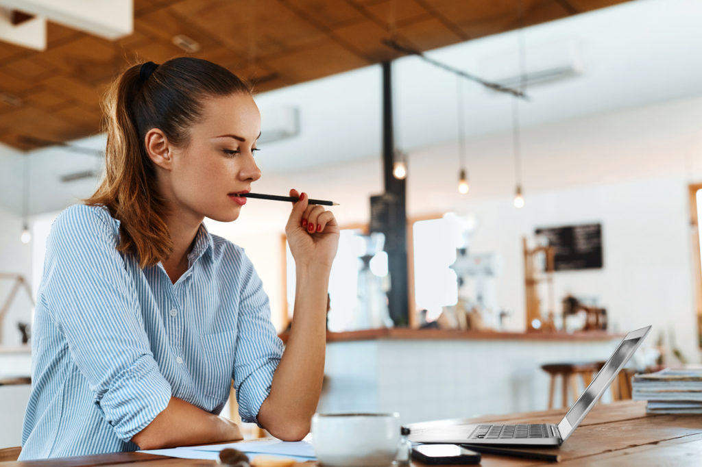 woman thinking about writing with pencil in mouth