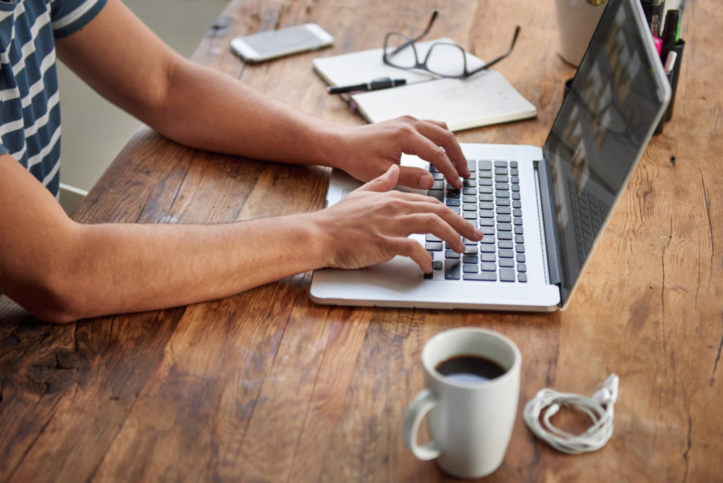 hands typing on a laptop writing